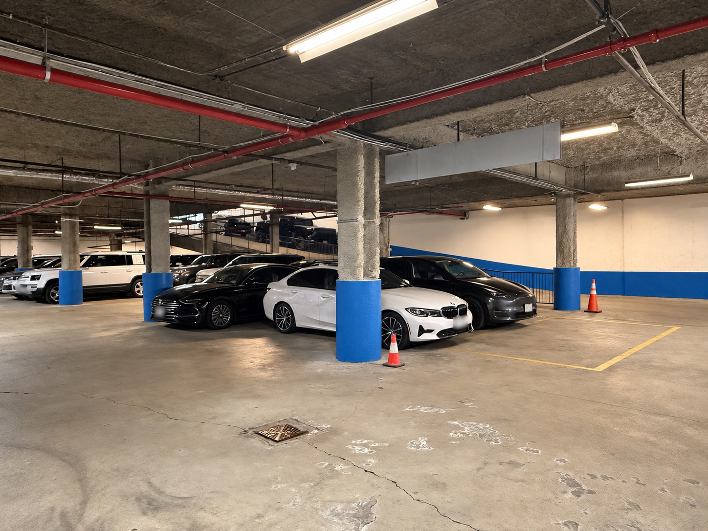Parked vehicles and marked spaces inside the garage at 125 Metropolitan Avenue