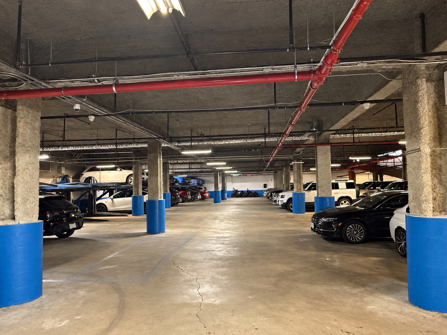 Interior drive aisle with parked vehicles and vehicle lifts at 125 Metropolitan Avenue